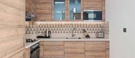 A modern kitchen with wooden cabinets, a built-in microwave, a gas stove, and a toaster.