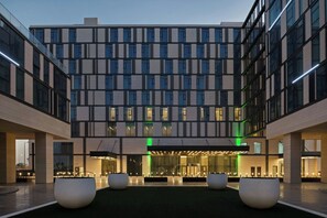 A modern hotel with a central courtyard, large planters, and a well-lit entrance. - Holiday Inn Dubai Al-Maktoum Airport by IHG (Dubai)
