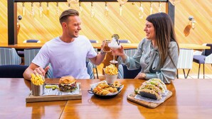 A restaurant with a wooden interior, hanging light fixtures, and a city view. - Holiday Inn Dubai Al-Maktoum Airport by IHG (Dubai)