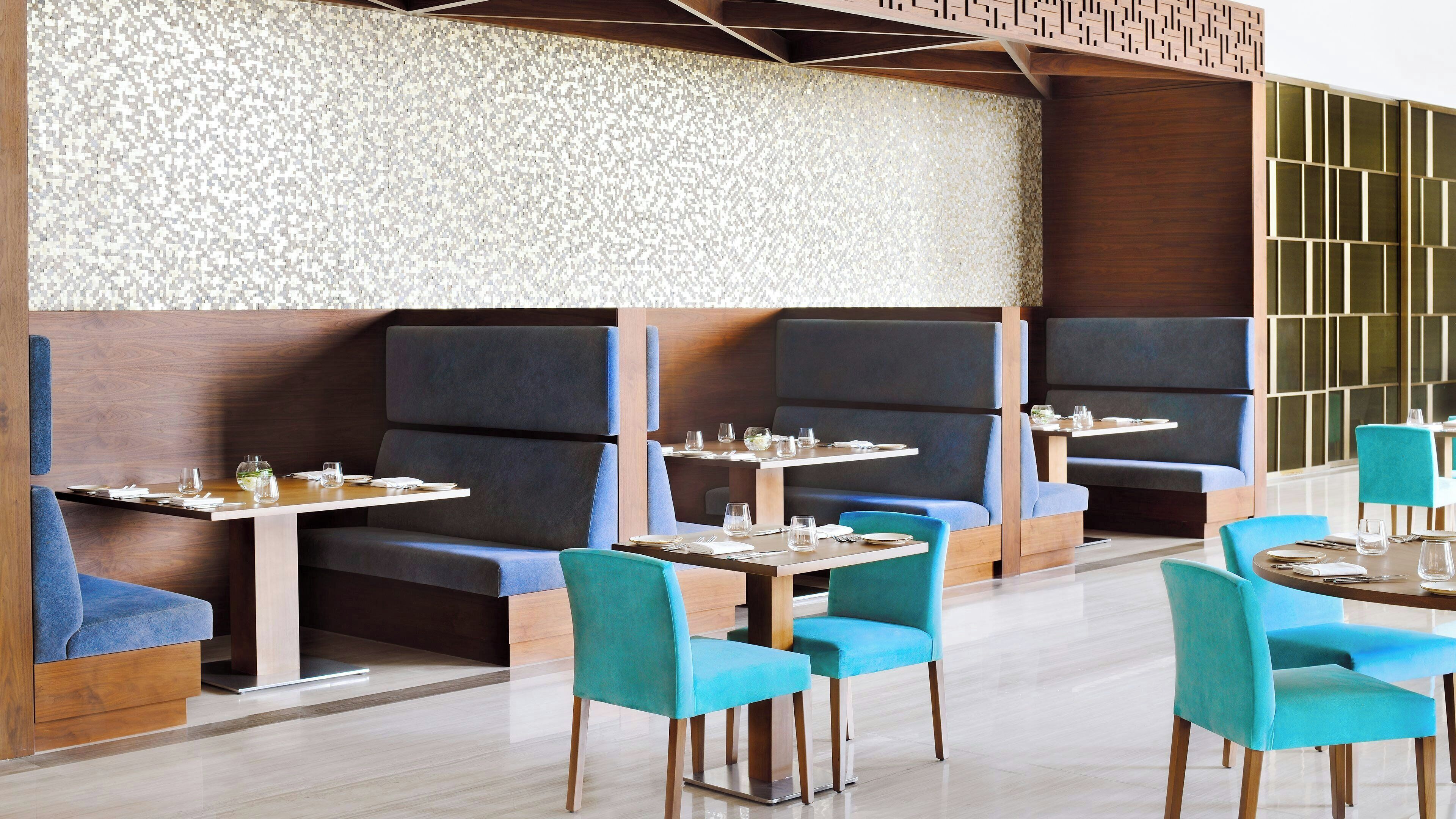 A modern restaurant with booth seating and round tables.