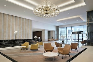 A spacious lobby with a modern chandelier, seating area, and large windows. - Holiday Inn Dubai Al-Maktoum Airport by IHG (Dubai)