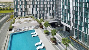A modern hotel with a rooftop pool, lounge chairs, and a view of the surrounding cityscape. - Holiday Inn Dubai Al-Maktoum Airport by IHG (Dubai)