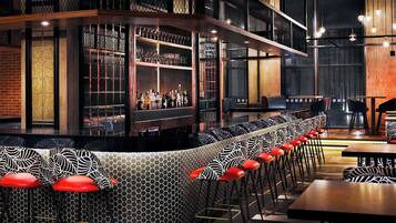 A bar area with a curved counter, seating with zebra-patterned cushions, and a variety of bottles on shelves.