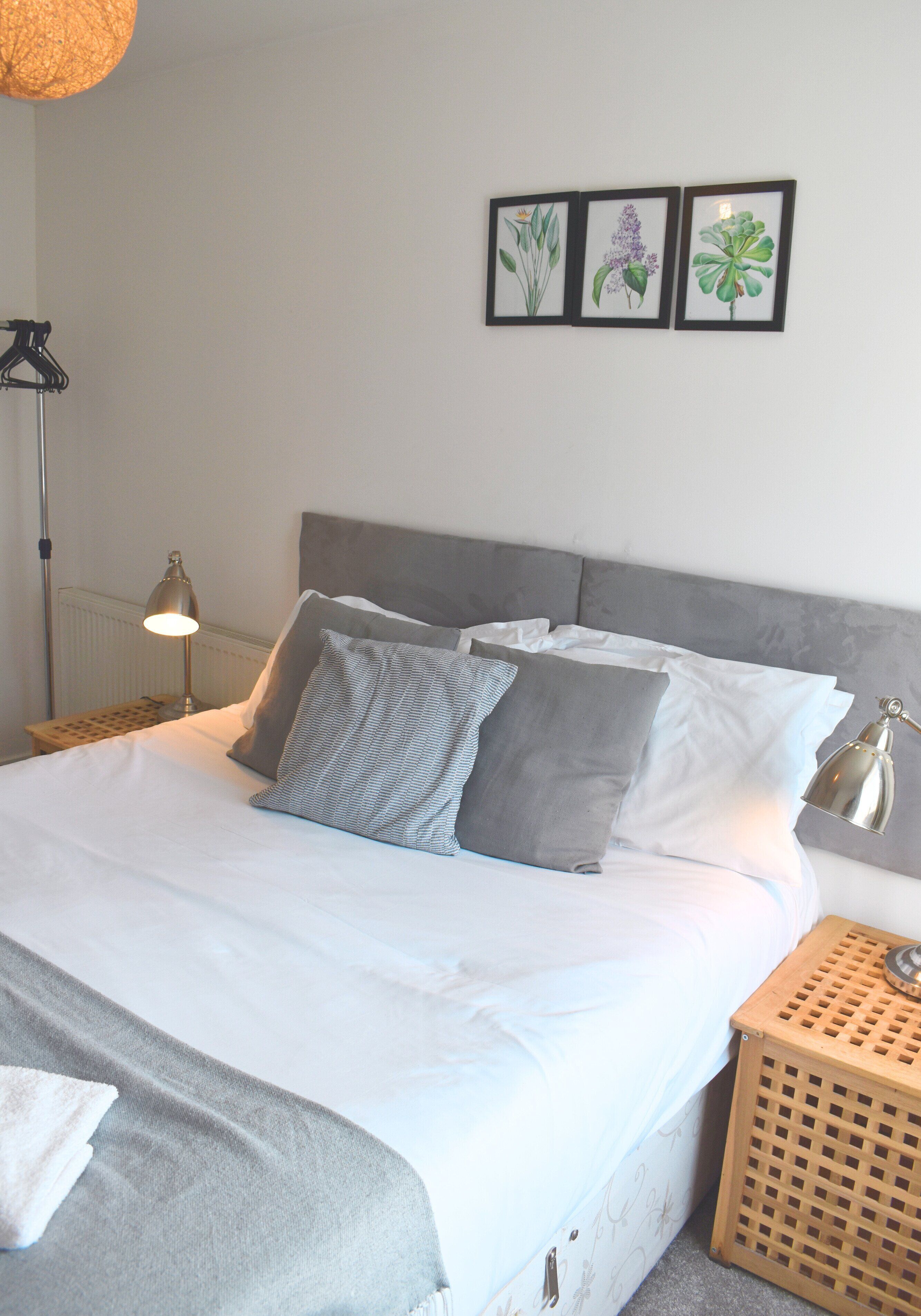 A neatly made bed with pillows, a bedside lamp, and a small wooden side table.