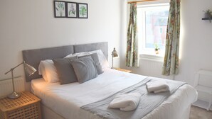 Un lit bien fait, avec des oreillers, une lampe de chevet et une fenêtre avec des rideaux.