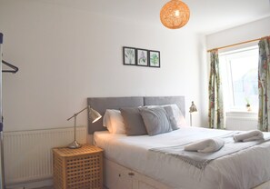Une chambre à coucher avec un lit, des lampes de chevet, un radiateur et une fenêtre avec des rideaux.