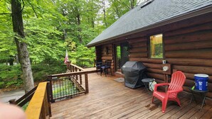 Eine Holzhütte mit einer Terrasse, einem Grill und Sitzgelegenheiten im Freien.