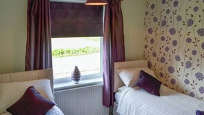 A room with two beds, a window with curtains, and a radiator. - The beach backed by sand dunes is just a short walk away. (California, near Great Yarmouth)