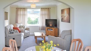 Ein Wohnzimmer mit Sofa, Fernseher und Essbereich, der für eine Mahlzeit gedeckt ist.
