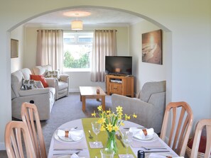 A living room with a sofa, TV, and dining area set for a meal.