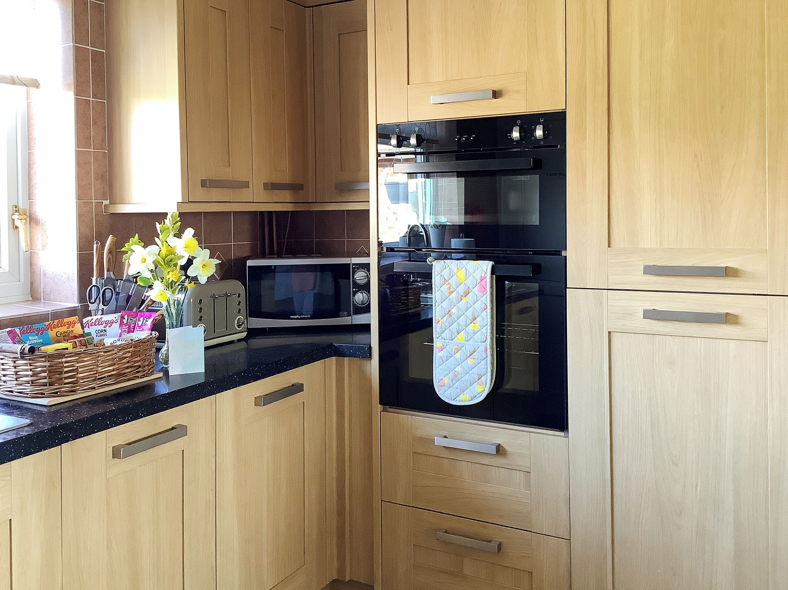 A modern kitchen with wooden cabinets, a black oven, a microwave, and a toaster.