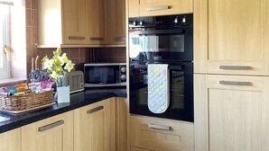 Eine moderne Küche mit Holzausstattung, einem schwarzen Backofen, einer Mikrowelle und einem Toaster.