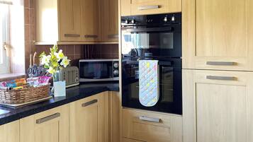 A modern kitchen with wooden cabinets, a black oven, a microwave, and a toaster.