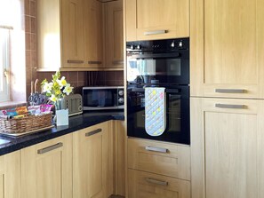 A modern kitchen with wooden cabinets, a black oven, a microwave, and a toaster.