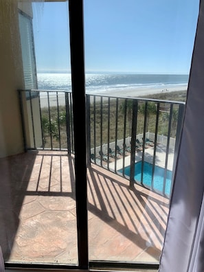 Un balcon avec vue sur l’océan et une piscine.