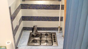 Una cocina compacta con estufa a gas, hervidor y una pequeña encimera.