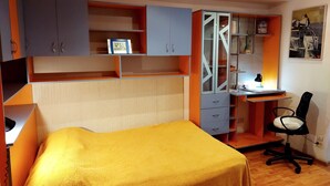 Un dormitorio con una cama, un escritorio y una silla. Hay un reloj en la pared.