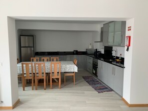 Eine kleine Küche mit Esstisch und Stühlen, einem Kühlschrank, einer Mikrowelle und Schränken.