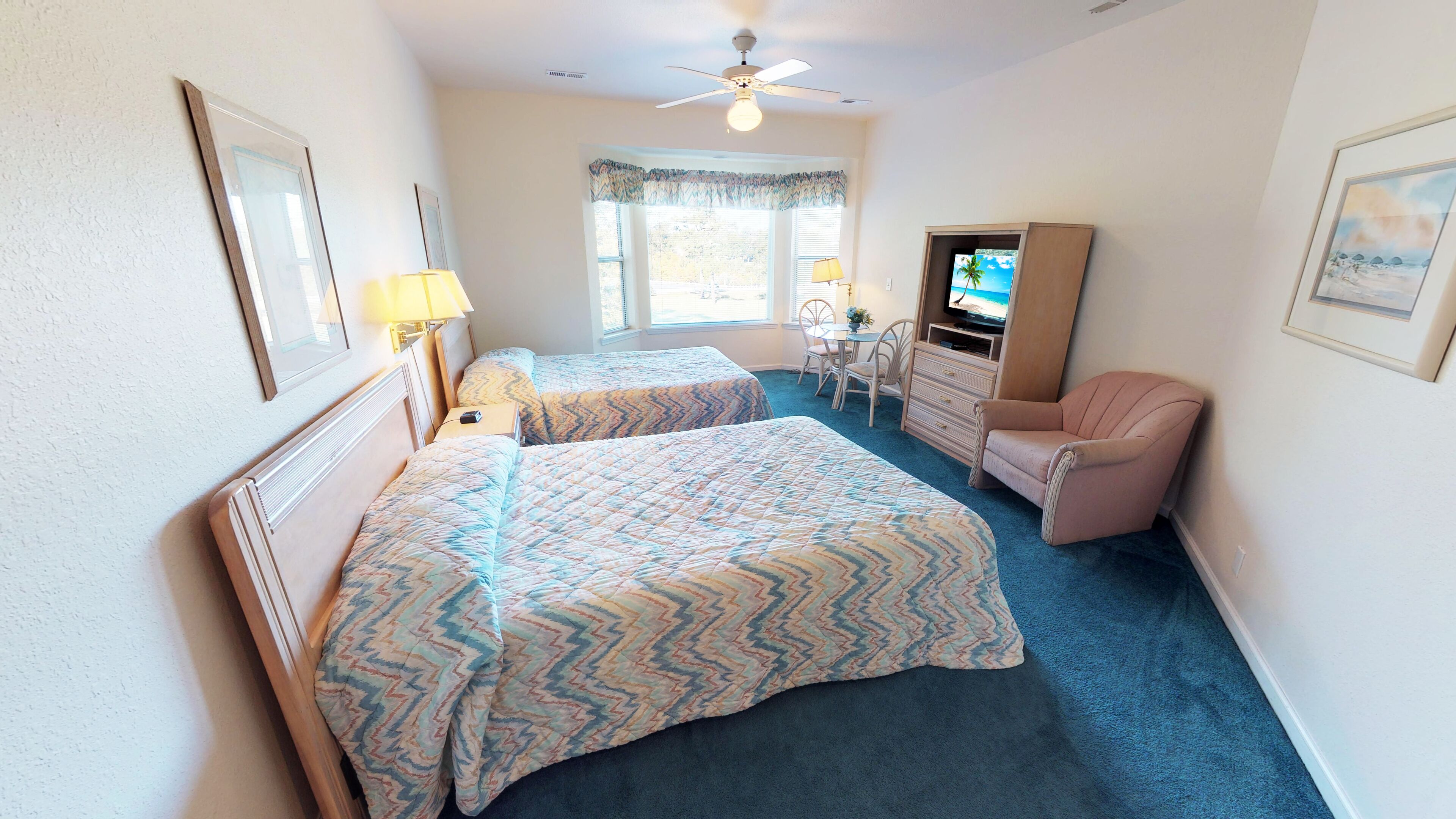 A hotel room with two beds, a TV, a desk, and a chair.