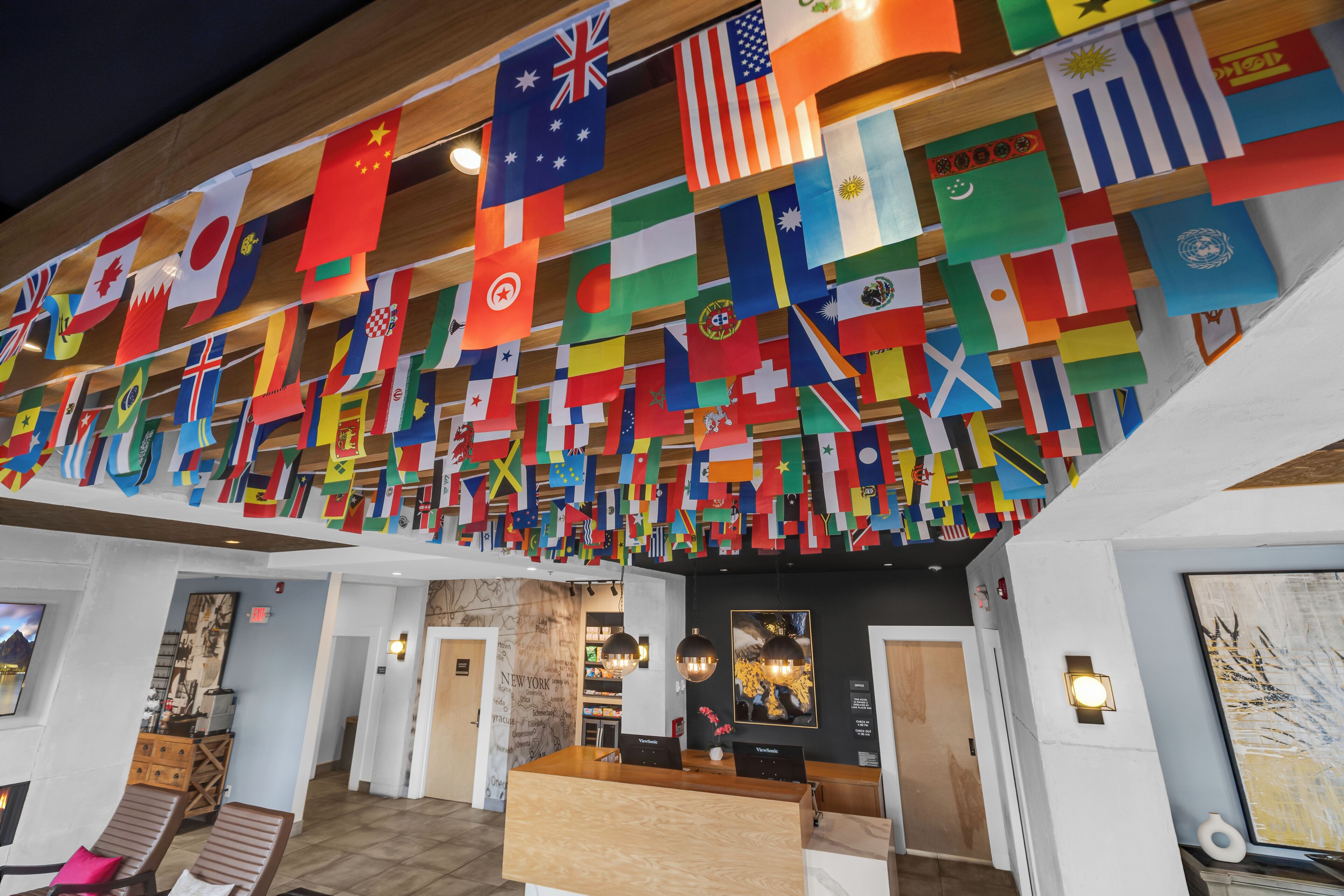 Eine Lobby mit einer Rezeption, Holzstühlen und einer Wand, die mit zahlreichen Nationalflaggen geschmückt ist.