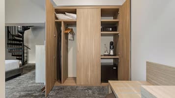 A bedroom with a bed, a wooden wardrobe, a desk, and a staircase.