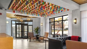 Un vestíbulo con diseño moderno, que incluye un mostrador de recepción, zona de estar y grandes ventanales con vistas al exterior.