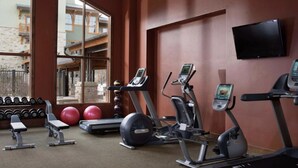 Ein Fitnessraum mit Laufbändern, Crosstrainern, Kurzhanteln und Gymbällen.