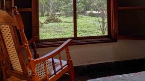 A room with a large arched window, a wooden chair, and a bed with a patterned bedspread. - Matagalpa la Tierra Land Of Dreams (San Ramon)