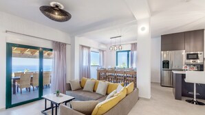 En moderne stue med sofa, spiseplads og køkken.