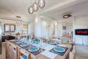 Une cuisine moderne avec un coin repas aménagé pour prendre un repas, un escalier menant à un autre niveau et un téléviseur affichant le logo de Netflix.