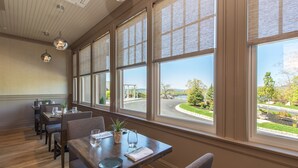 Un comedor con ventanas amplias, mesas y sillas de madera.