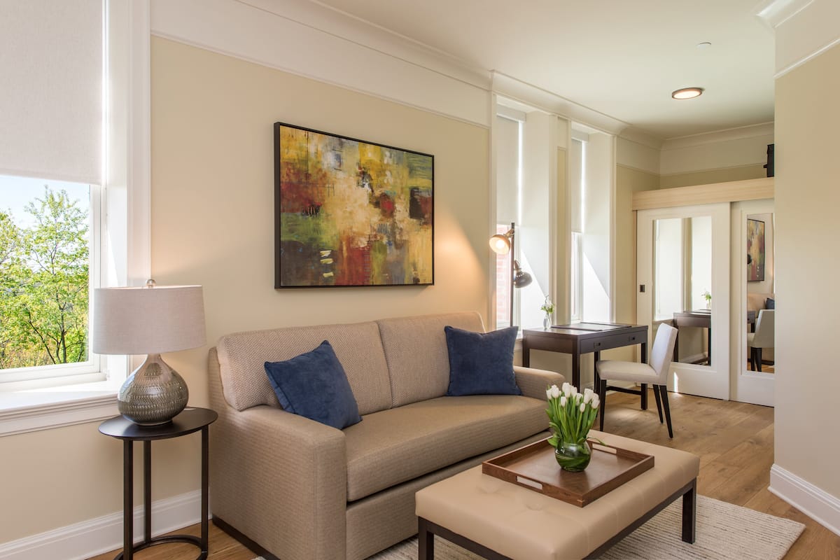 A living room with a beige sofa, a coffee table, a lamp, and a painting on the wall.
