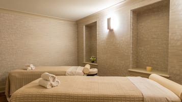 Two beds and a bedside table with a candle create a serene atmosphere.