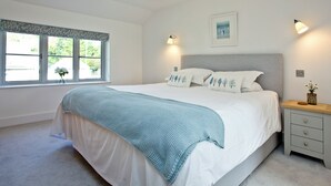 A bedroom with a bed, bedside tables, a window, and a wall-mounted light fixture. - 4 bedroom accommodation in Trelights, near Port Isaac (Trelights, near Port Isaac)