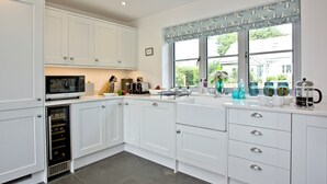 A modern kitchen with white cabinets, a built-in wine cooler, a large window with a view, and a hanging light fixture. - 4 bedroom accommodation in Trelights, near Port Isaac (Trelights, near Port Isaac)