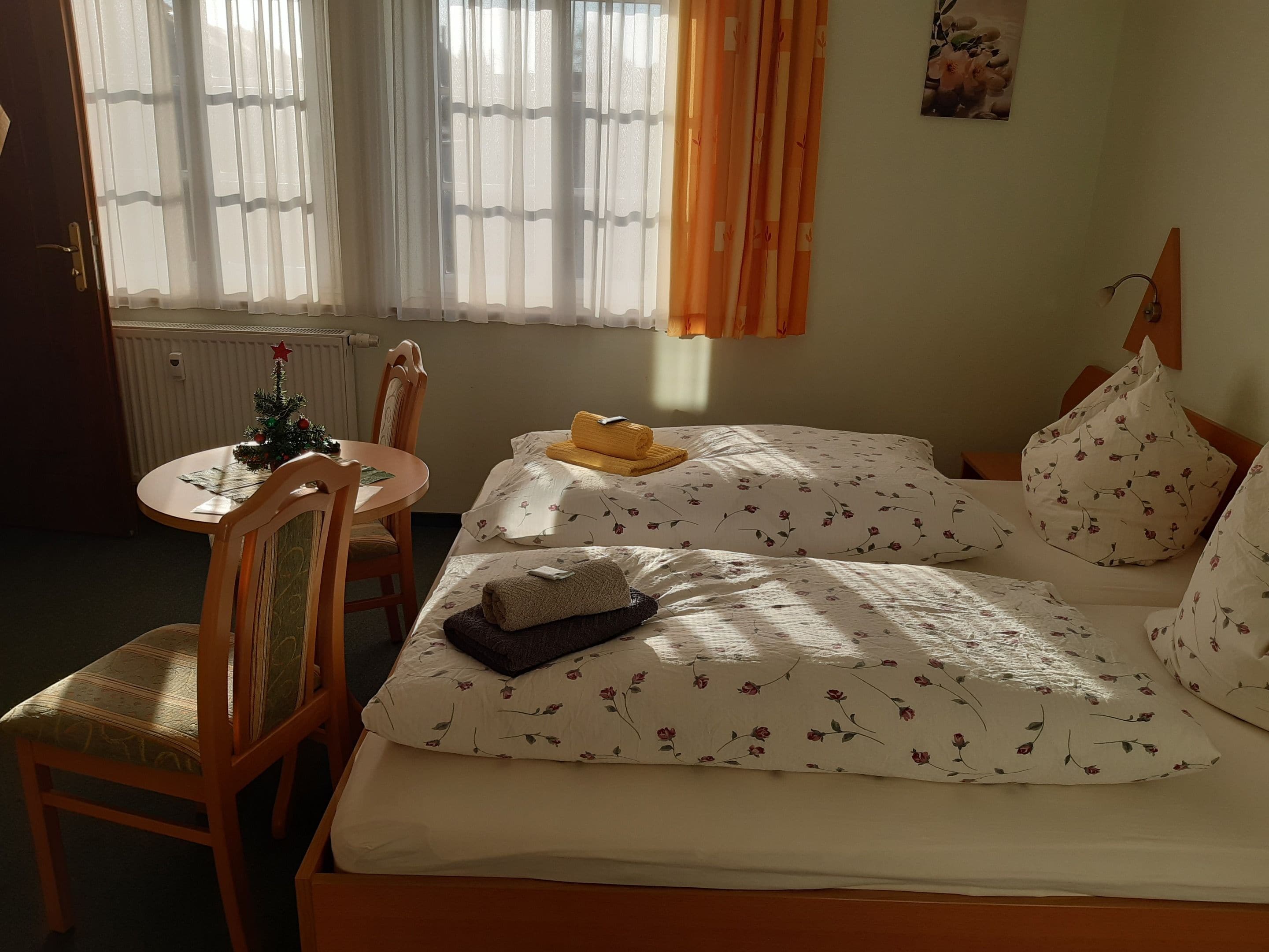 Une chambre d’hôtel avec un lit, une chaise, une petite table et un radiateur.