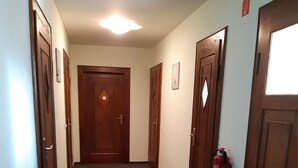 A hallway with wooden doors, a fire extinguisher, and a radiator. - Pension Schöne (Grossrohrsdorf)
