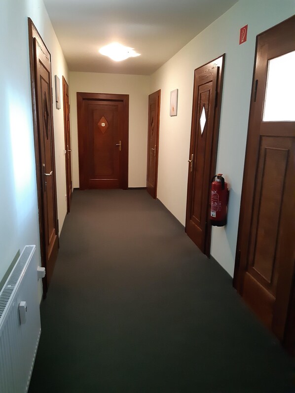 A hallway with wooden doors, a fire extinguisher, and a radiator.