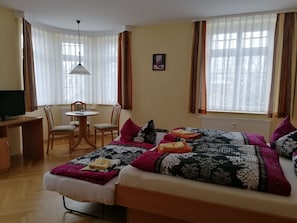 Un dormitorio con cama, escritorio y silla. Hay una ventana con cortinas y un cuadro en la pared.