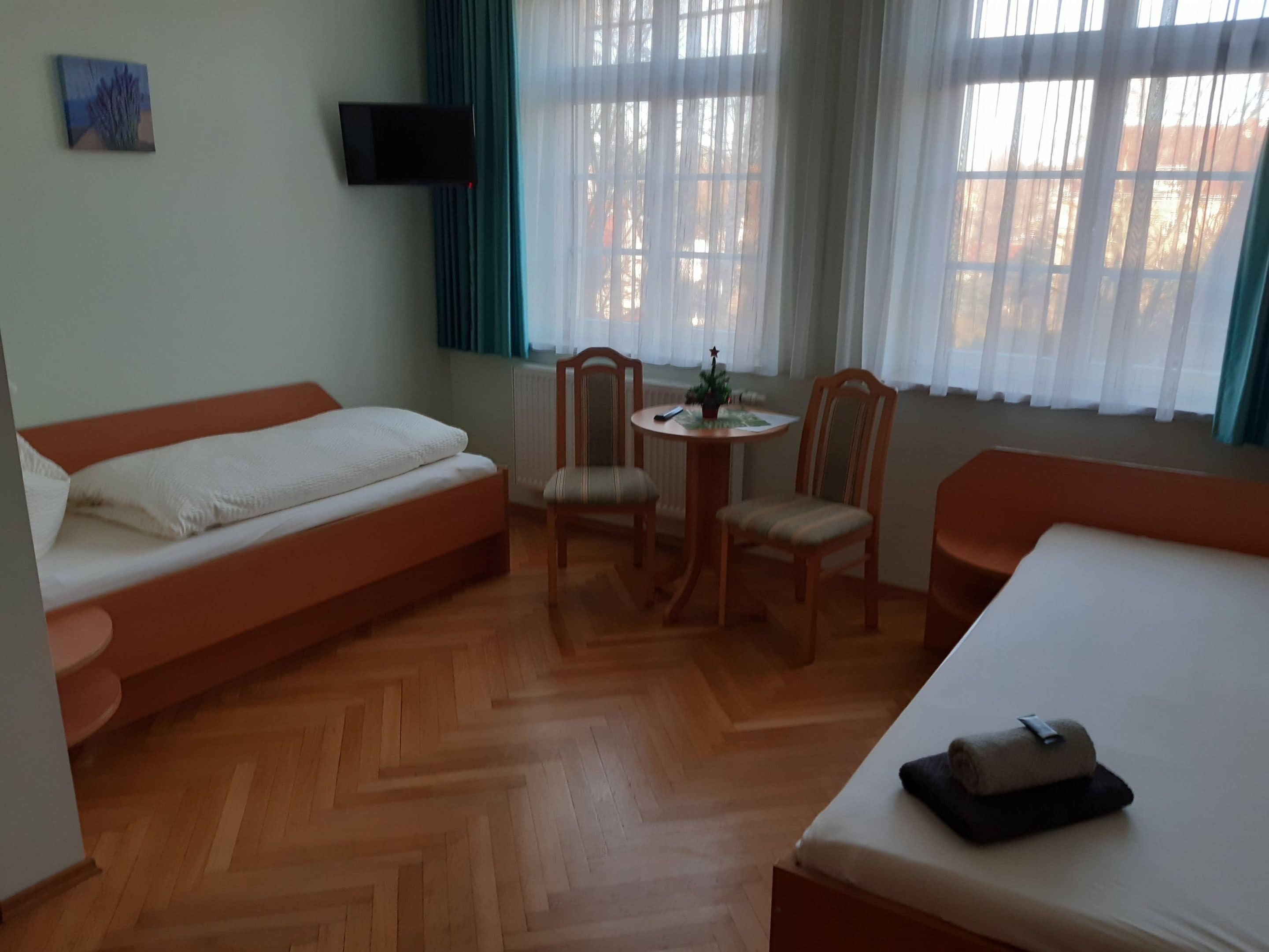 Huoneessa on sänky, sohva, pieni pöytä tuoleineen sekä seinälle asennettu televisio.