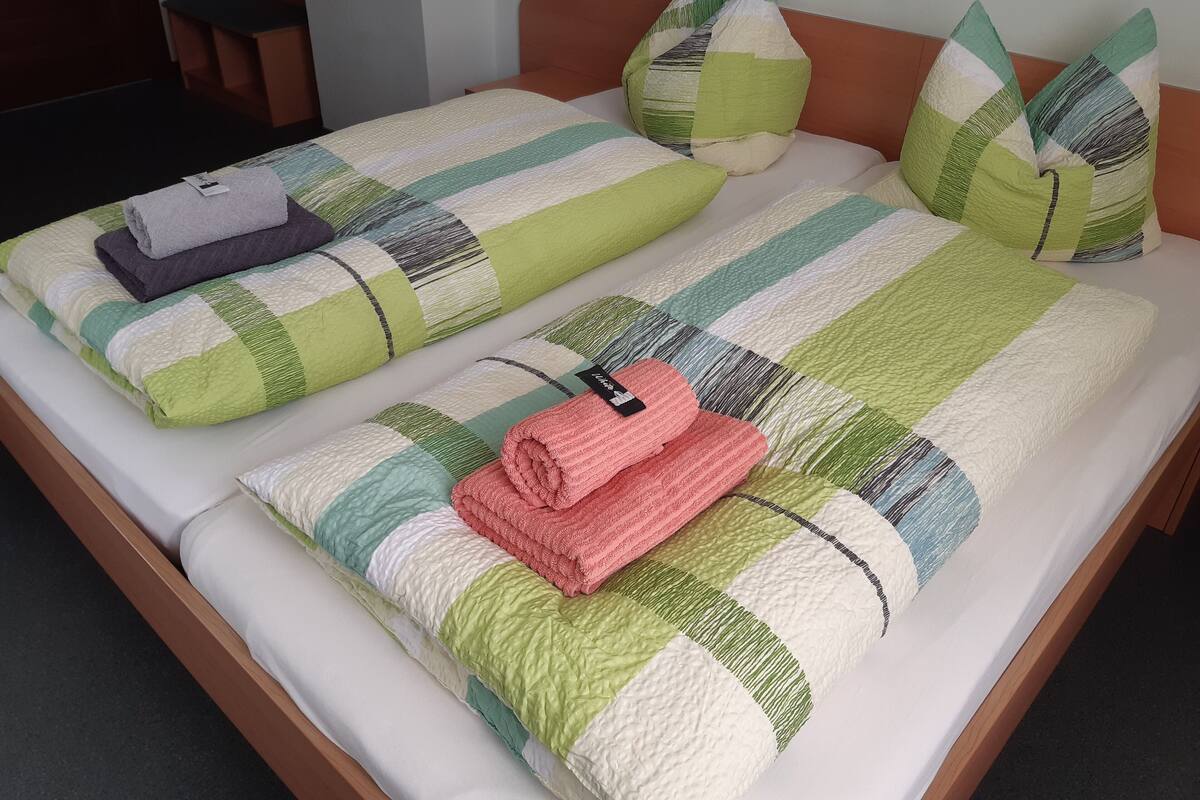 Un lit double avec une literie à rayures et des oreillers, une tête de lit en bois et une petite table avec une chaise.