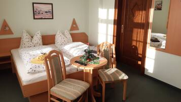 Une chambre à coucher avec un lit, deux chaises, une petite table, un sapin de Noël et un tableau accroché au mur.