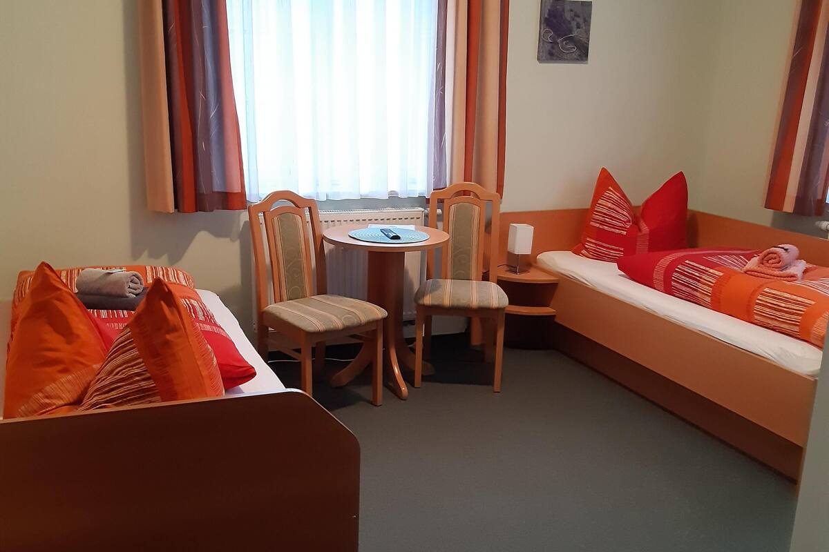Une pièce confortable avec un canapé, deux fauteuils, une petite table et une fenêtre avec des rideaux.