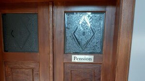A wooden door with a frosted glass panel and a sign that reads "Pension." - Pension Schöne (Grossrohrsdorf)