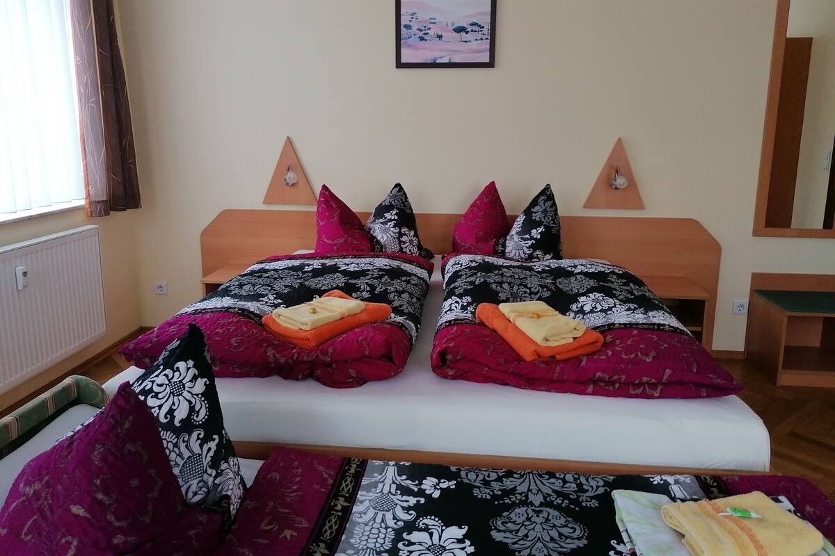 Un lit double avec une literie à motifs et des oreillers, une table de chevet, un miroir et un tableau encadré au mur.