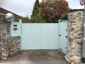A light blue gate with a stone wall on one side and a metal gate on the other.