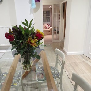A dining area with a glass table, chairs, and a vase of flowers.
