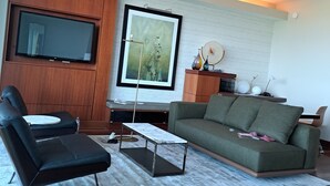 A modern living room with a flat-screen TV, a green sofa, a black leather chair, and a marble coffee table. - Privately managed 2BR+ 2,5Bath  best line oceanfront at the Ritz  Bal Harbour  (Bal Harbour)