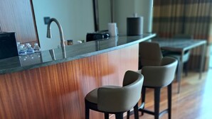 A modern kitchen with a wooden countertop, two bar stools, a sink, and a dining area with a table and chairs. - Privately managed 2BR+ 2,5Bath  best line oceanfront at the Ritz  Bal Harbour  (Bal Harbour)