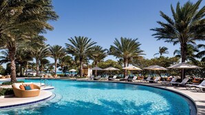 A pool area with lounge chairs and umbrellas, surrounded by palm trees. - Privately managed 2BR+ 2,5Bath  best line oceanfront at the Ritz  Bal Harbour  (Bal Harbour)
